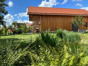 ein Holzhaus mit einem Grasfeld davor in der Unterkunft Ferienhaus Königsdorf - Urlaub im Tölzer Land in Königsdorf
