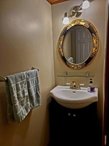 a bathroom with a sink and a mirror and towels at Gîte du passant SADM, parc de la Gaspésie. in Sainte-Anne-des-Monts