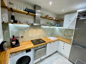 eine Küche mit weißen Schränken, einer Waschmaschine und einem Trockner in der Unterkunft Traveller Award Winner 2023 - Edinburgh Apartment with 3 Beds in Edinburgh