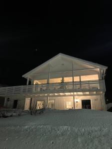 een groot wit huis 's nachts in de sneeuw bij Apartment with a unique view, center of Kvaløya in Tromsø