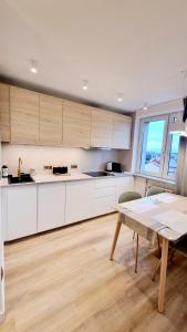 a kitchen with white cabinets and a wooden table at Apartament Spokojna przy SUNTAGO DEEPSPOT Mszczonów in Mszczonów