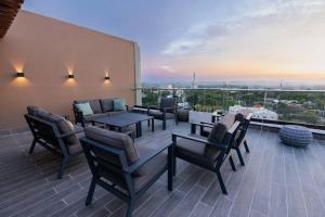 a patio with chairs and tables on a roof at Modern 2BR in La Trinitaria Sti No in Santiago de los Caballeros