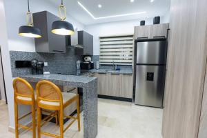 a kitchen with a counter with two chairs and a refrigerator at Modern 2BR in La Trinitaria Sti No in Santiago de los Caballeros