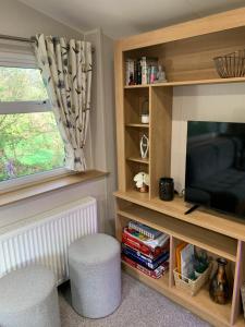 a living room with a television and two stools at 4 Devon Country, Bideford Bay Holiday Park in Bucks Mills