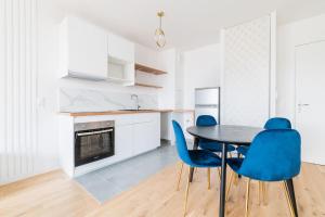 a kitchen with a dining table and blue chairs at L'Elégante Oasis - grand T2 aux portes de Paris in Saint-Ouen