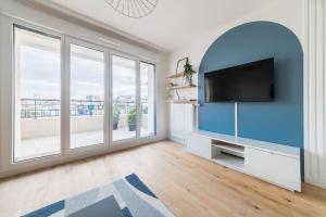 a living room with a tv and a large window at L'Elégante Oasis - grand T2 aux portes de Paris in Saint-Ouen