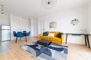 a living room with a yellow couch and a table at L'Elégante Oasis - grand T2 aux portes de Paris in Saint-Ouen