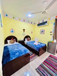een slaapkamer met 2 bedden met blauwe lakens bij Nukud guest house in Aswan