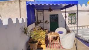 een patio met een tafel en stoelen en een blauwe parasol bij Riad en el corazón de la Medina in Tetouan