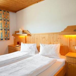 een slaapkamer met 2 bedden met witte lakens en kussens bij Tofererhof in Bad Hofgastein