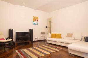 a living room with a white couch and a tv at Mazzini House in Turin