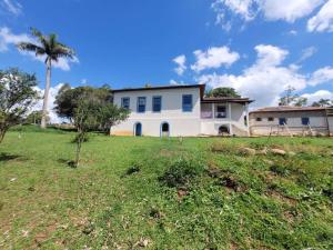 ein großes weißes Haus mit einer Palme auf einem Feld in der Unterkunft Fazenda centenária no Sul de MG 