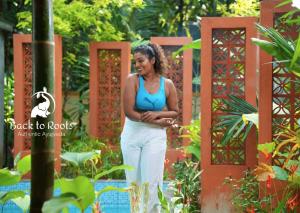 una mujer parada en medio de un jardín en Back to Roots Ayurveda Retreat en Kizhake Chālakudi