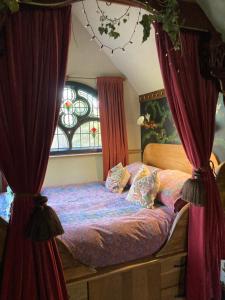 a bedroom with a bed with curtains and a window at Enchanting Hand Painted Tabernacle with Hot Tub in Bude