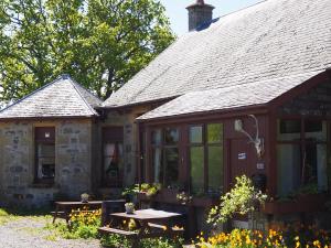 uma casa com uma mesa de piquenique em frente em Uist Cottage em Kingussie