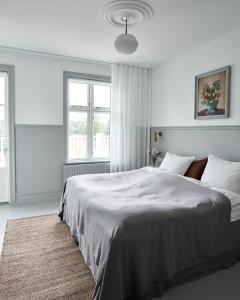 a white bedroom with a large bed and two windows at Hotel Ny Hattenæs in Silkeborg