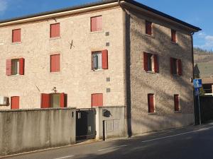 ein großes Backsteingebäude mit roten Fenstern und einer Tür in der Unterkunft CASA TOFFOLI SOLIGO - locazioni turistiche in Soligo