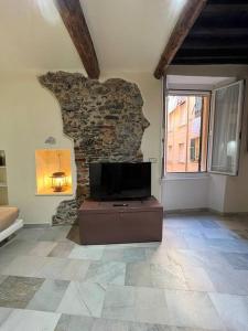 a living room with a tv and a stone wall at Iris 3: Un Fiore a Camogli in Camogli