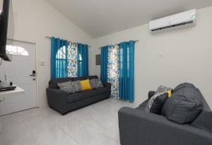 sala de estar con 2 sofás y cortinas azules en Osmax Oasis/One bedroom en Discovery Bay