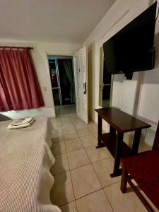 una habitación con una cama y una mesa y un televisor en Los Nonos, en Villa Cura Brochero