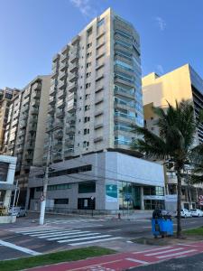 a tall building with a palm tree in front of it at Ocean Flat com vista pro mar 604 in Vila Velha