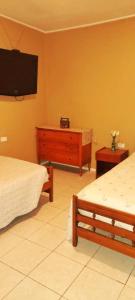 1 dormitorio con 2 camas y TV en la pared en B&B Hogar Bella Vita, en Coquimbo