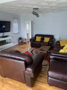 uma sala de estar com sofás de couro e uma televisão em Coastal home em Kent