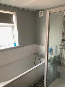 ein Bad mit einer Badewanne und einem Fenster in der Unterkunft Coastal home in Kent