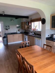 uma grande cozinha com uma mesa de madeira e cadeiras em Coastal home em Kent