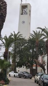 una torre del reloj con coches estacionados en un estacionamiento en Cal Xot, en El Poblenou del Delta
