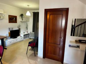 een woonkamer met een houten deur en een televisie bij Casa rural Campiña de Sevilla Tranquila y familiar 