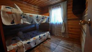 a bedroom with a bed and a window in a log cabin at ENTRE PINOS Y LUCEROS ACOGEDORA CABAÑA RÚSTICA in Villarrica