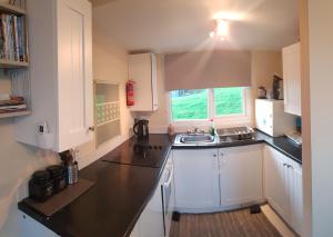 uma cozinha com armários brancos e um lavatório em 9 Sea Valley em Clovelly