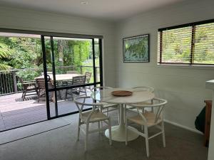 a dining room with a table and chairs and a patio at The Bach at Te Toki in Palm Beach +2 photos