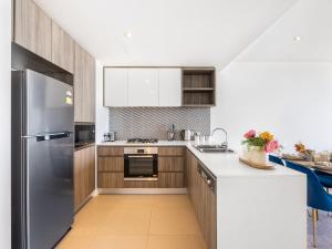 een keuken met houten kasten en een roestvrijstalen koelkast bij Amazing cityview Glamourous 2BR Apt w parkpool in Brisbane