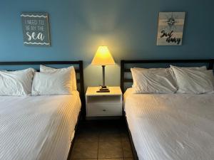 1 dormitorio con 2 camas y mesita de noche con lámpara en Seagrass Inn, en Old Orchard Beach