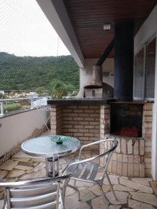 patio con mesa, sillas y horno al aire libre en Solar Diamantina Apartamentos, en Florianópolis