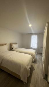 Habitación con 2 camas, paredes blancas y suelo de madera. en Appartement avec jardinet, quartier pavillonnaire, en Argenteuil