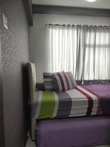 een slaapkamer met een bed met een raam en een kussen bij The jarddin apartment 2BR by kanaya in Bandung