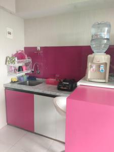 uma cozinha cor-de-rosa e branca com um lavatório e uma batedeira em The jarddin apartment 2BR by kanaya em Bandung