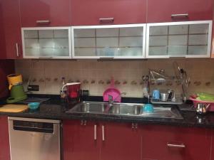 a kitchen with red cabinets and a stainless steel sink at Gessy in Salé