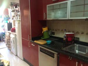 a kitchen with red cabinets and a sink and a refrigerator at Gessy in Salé