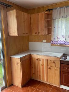 una cocina vacía con armarios de madera y una ventana en Cabañas Rayen, en Riñinahue