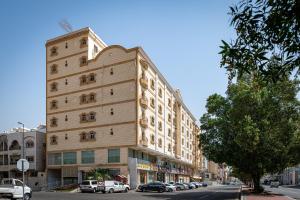 Holiday Plus Al Salamh- هوليداي بلس السلامه في جدة: مبنى كبير على شارع المدينة فيه سيارات متوقفة