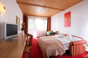 キルヒベルク・イン・チロルにあるAlpenhotel Landhaus Küchlのベッドとテレビが備わるホテルルームです。