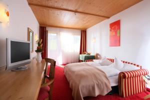a hotel room with a bed and a television at Alpenhotel Landhaus Küchl in Kirchberg in Tirol
