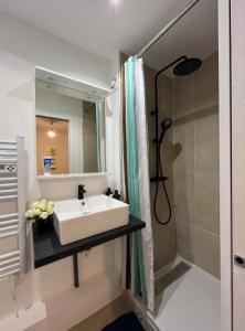 een badkamer met een witte wastafel en een douche bij Studio Émeraude au centre-ville in Villejuif
