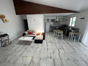 a living room with a couch and a table and a kitchen at SLM - Le clos Gaïac - A in Saint-Laurent du Maroni