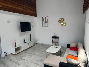 a living room with a couch and a tv at SLM - Le clos Gaïac - A in Saint-Laurent du Maroni