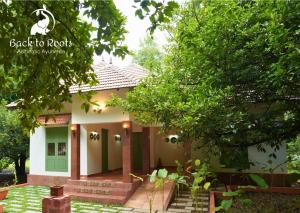 a small house with a green door and trees at Back to Roots Ayurveda Retreat in Kizhake Chālakudi